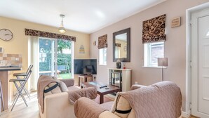 A cozy living room with a sofa, armchairs, a TV, and a fireplace. - 2 bedroom accommodation in Bridlington (Bridlington)