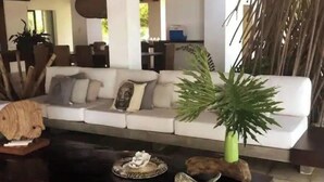 Un salon moderne avec un canapé blanc, une table basse et des objets décoratifs, notamment une plante et une sculpture.