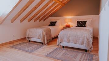 A cozy attic bedroom with two beds, wooden beams, and a lamp.