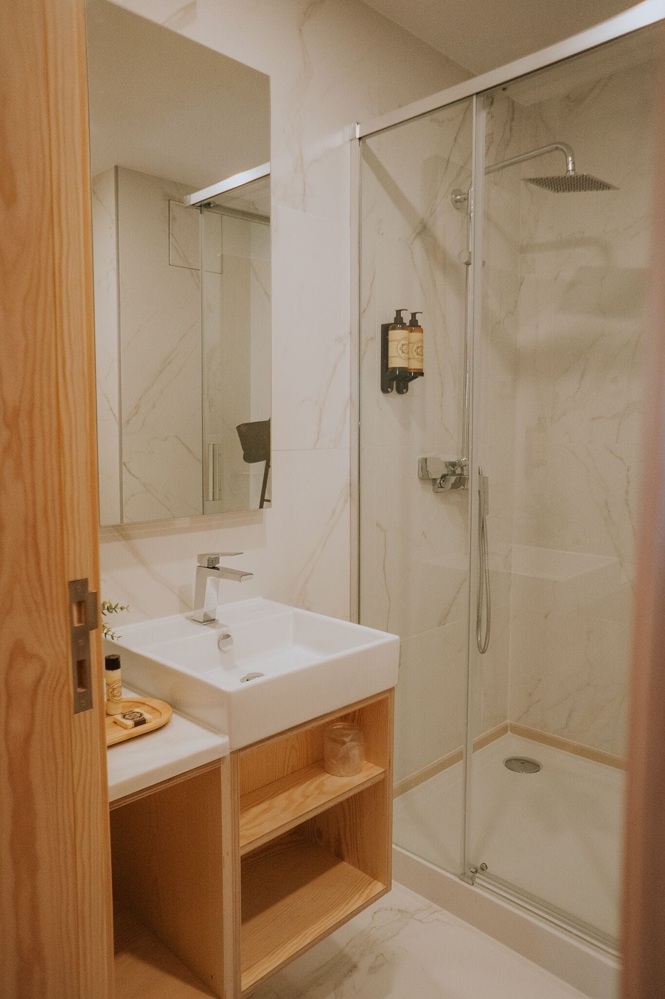 A modern bathroom with a glass-enclosed shower, a white sink, and a wooden vanity.