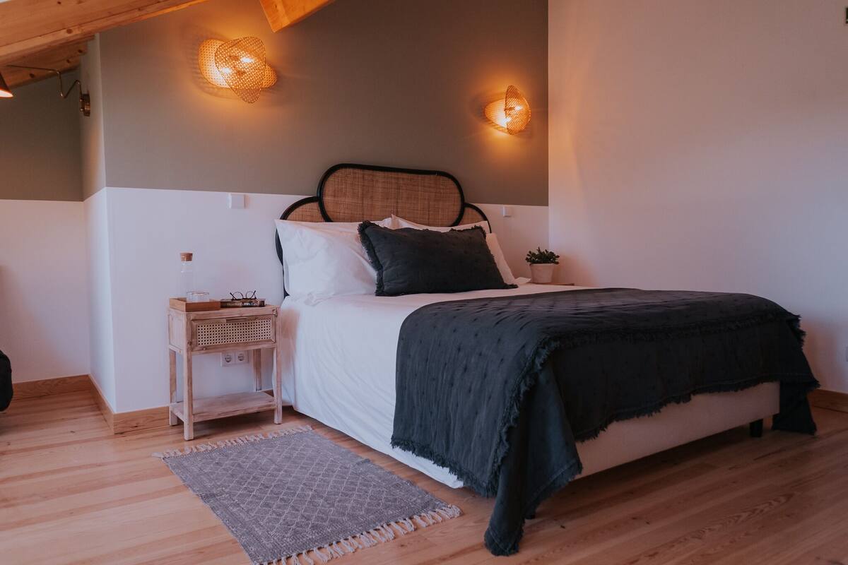 A bedroom with a bed, bedside table, lamp, and a small potted plant.