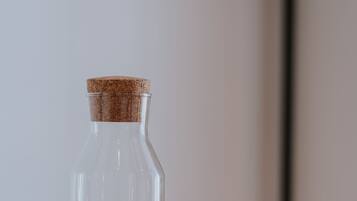 Een glazen fles met kurkprop op een houten ondergrond.