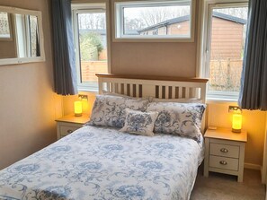 A bedroom with a bed, two bedside tables, and a window with curtains.