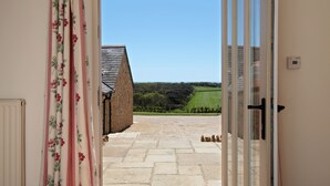 A doorway leading to a stone-floored courtyard with a view of a rural landscape. - Clayhanger Lodge  - Abbotsbury, Dorset (Abbotsbury)
