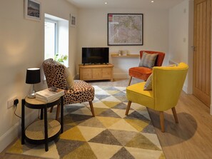 Ein Wohnzimmer mit Sofa, Sessel, Fernseher und einer Karte an der Wand.