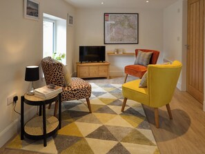 Ein Wohnzimmer mit Sofa, Sessel, Fernseher und einer Karte an der Wand.
