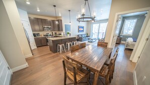 A spacious kitchen with a central island, wooden dining table, and bar stools. - Clearwater Lofts Bldg 2 203 (Keystone)