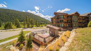 A multi-story building with balconies, a parking lot, and a mountainous backdrop. - Clearwater Lofts Bldg 2 203 (Keystone)