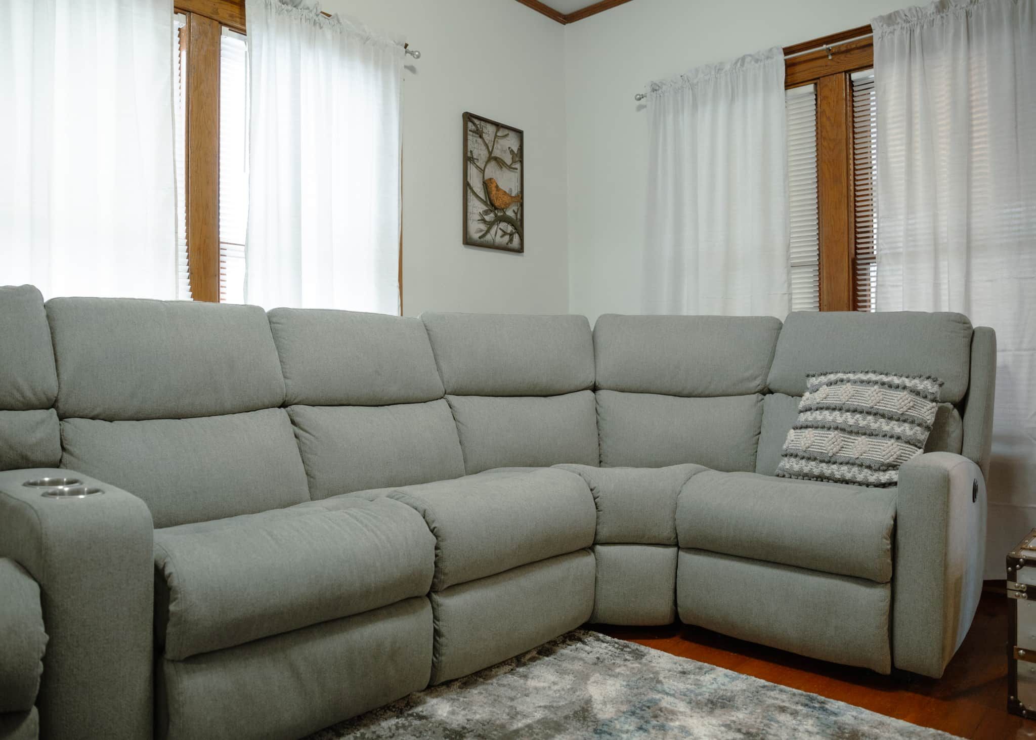 Un canapé modulable doté d’une table d’appoint intégrée, d’un coussin décoratif et d’un tableau encadré accroché au mur.