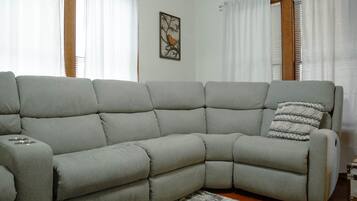 Un canapé modulable doté d’une table d’appoint intégrée, d’un coussin décoratif et d’un tableau encadré accroché au mur.