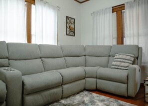 Un divano componibile con un tavolino integrato, un cuscino decorativo e un quadro appeso al muro.