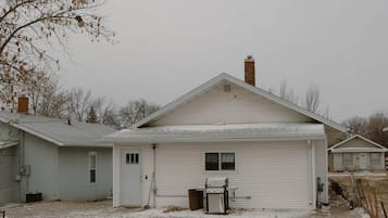 A single-story house with a garage, a chimney, and a gravel driveway.
