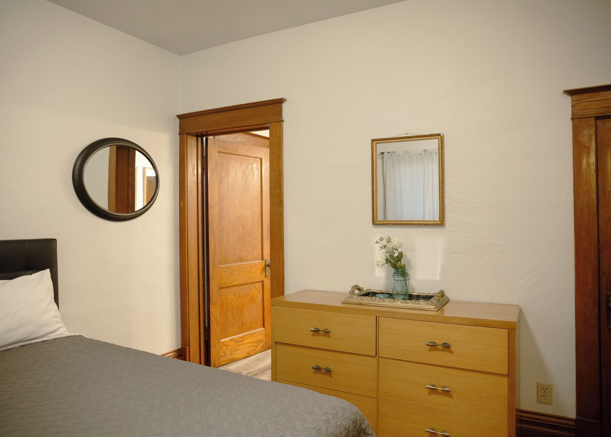 A bedroom with a bed, a dresser, a mirror, and a door.