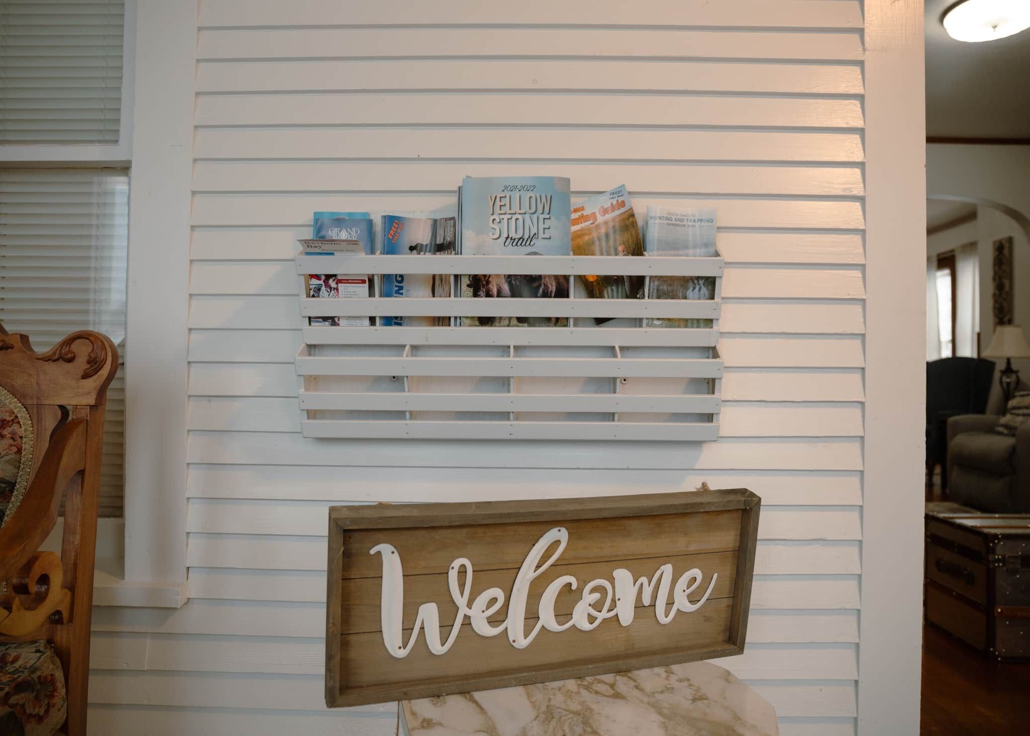 A wall with a 'Welcome' sign and a shelf with books and a 'Yellow Stone Trail' sign.