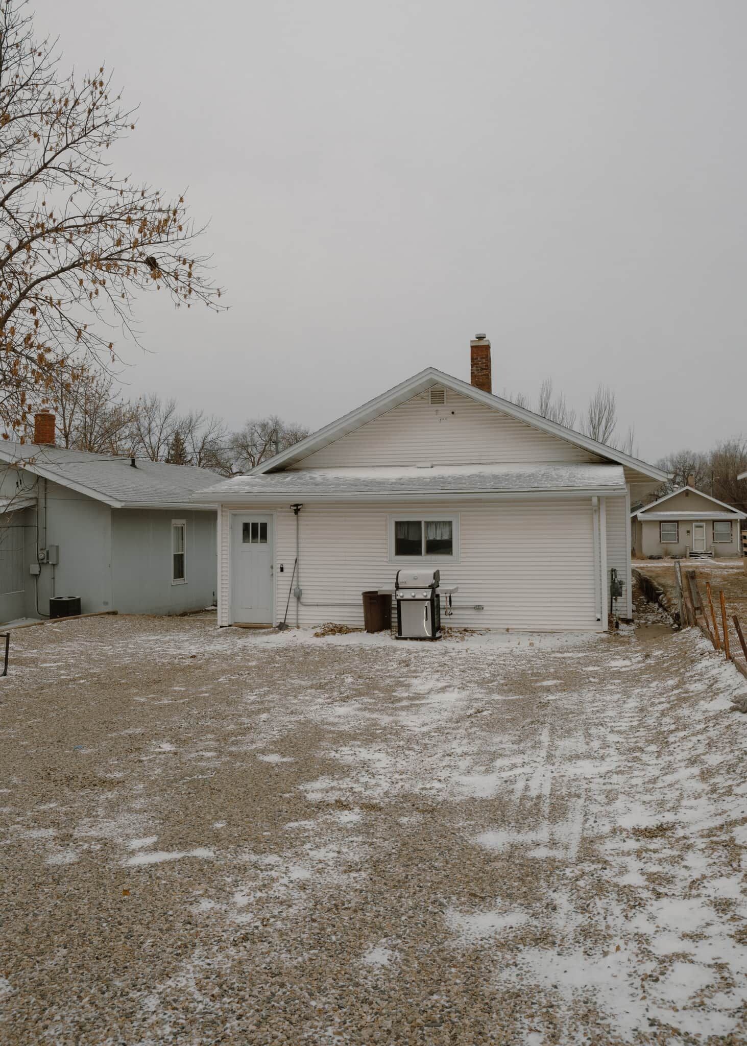 A single-story house with a garage, a chimney, and a gravel driveway.