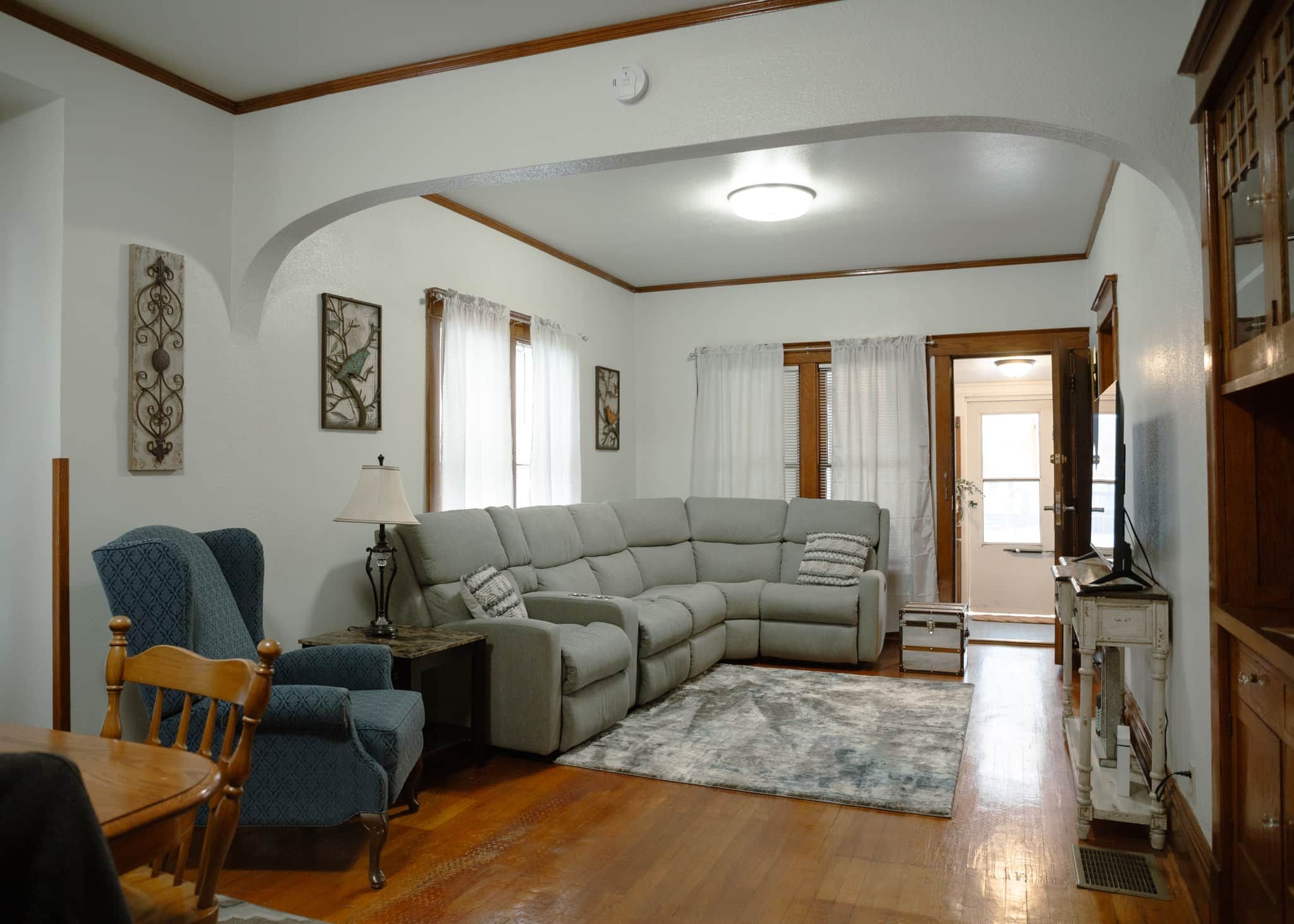 A living room with a sectional sofa, a wooden dining table, chairs, and a television.