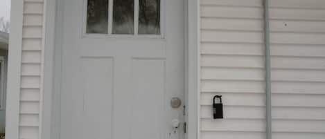 A white door with a window above it, a lock on the door, and a utility pole to the right.