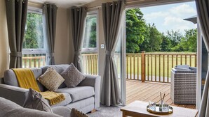 Ein gemütliches Wohnzimmer mit grauem Sofa, gelber Decke und einem Holztisch.
