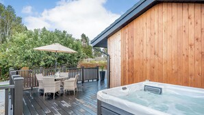 A wooden deck with a hot tub, outdoor furniture, and a wooden fence.