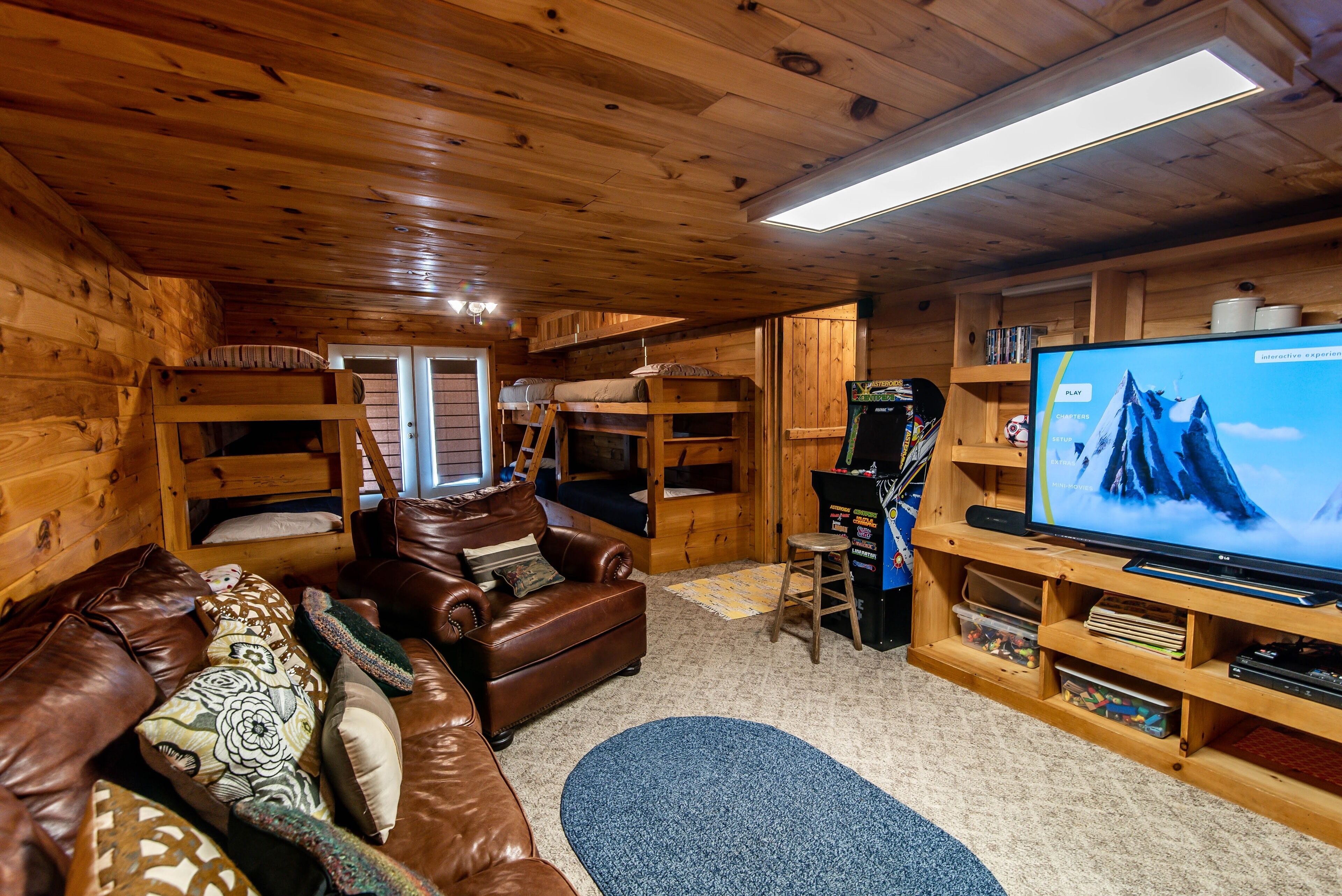 A cozy cabin interior with a brown leather couch, a television, and a wooden entertainment unit.