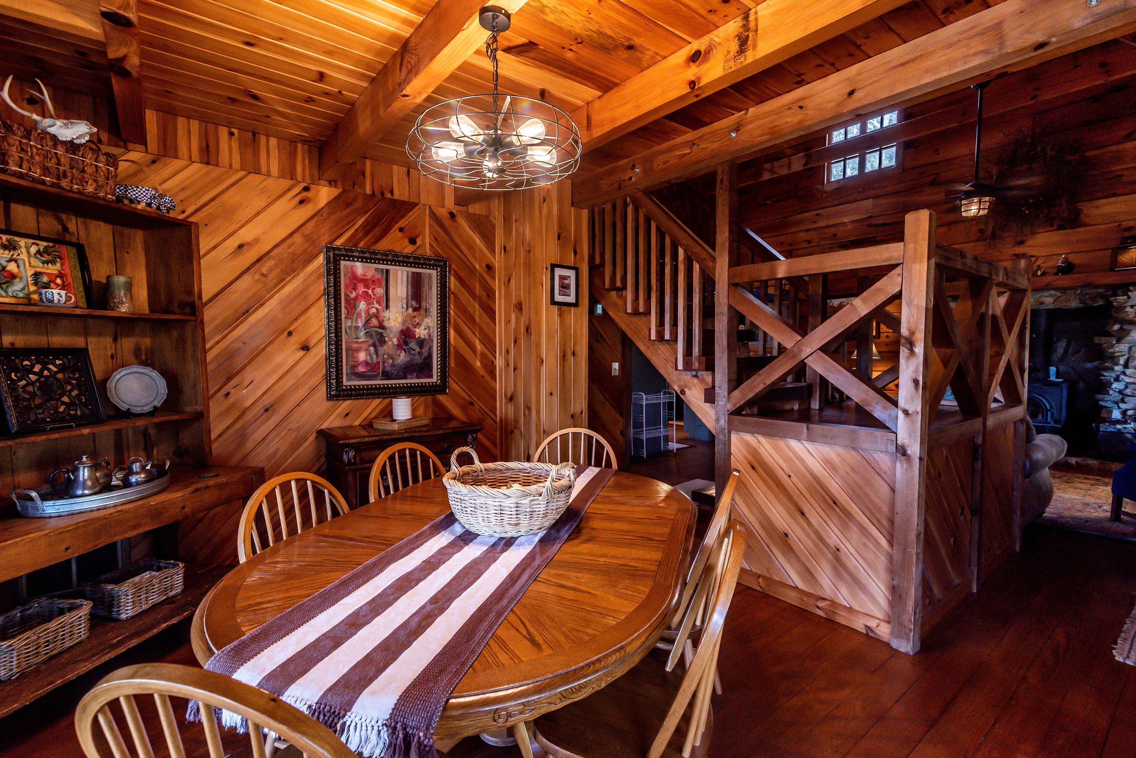 A wooden dining room with a large table, chairs, and a chandelier.