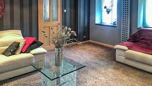 Un salon avec un canapé beige, une table basse en verre et une porte dont les panneaux sont en verre dépoli.