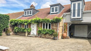 Une maison à deux étages, avec un toit en tuiles, un petit porche à l’avant et un garage.