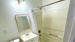 Un baño con inodoro, lavamanos, espejo y ducha.