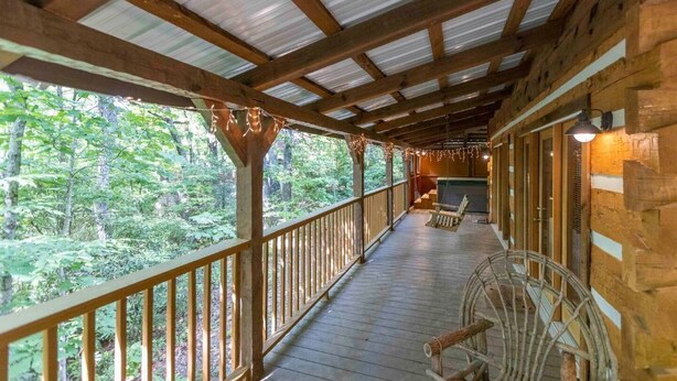 A wooden deck with a railing overlooking a forested area. - “The Creel” Luxury 2BR Cabin with loft & view (Townsend)