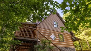 A wooden cabin with a balcony, stone foundation, and a staircase leading to the upper level. - “The Creel” Luxury 2BR Cabin with loft & view (Townsend)