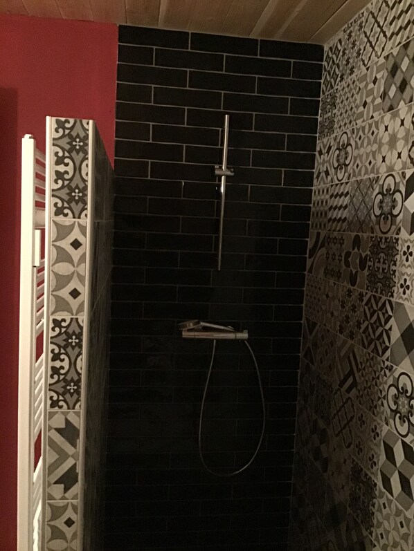 Un baño con ducha, paredes de azulejos y una pared de acento roja.