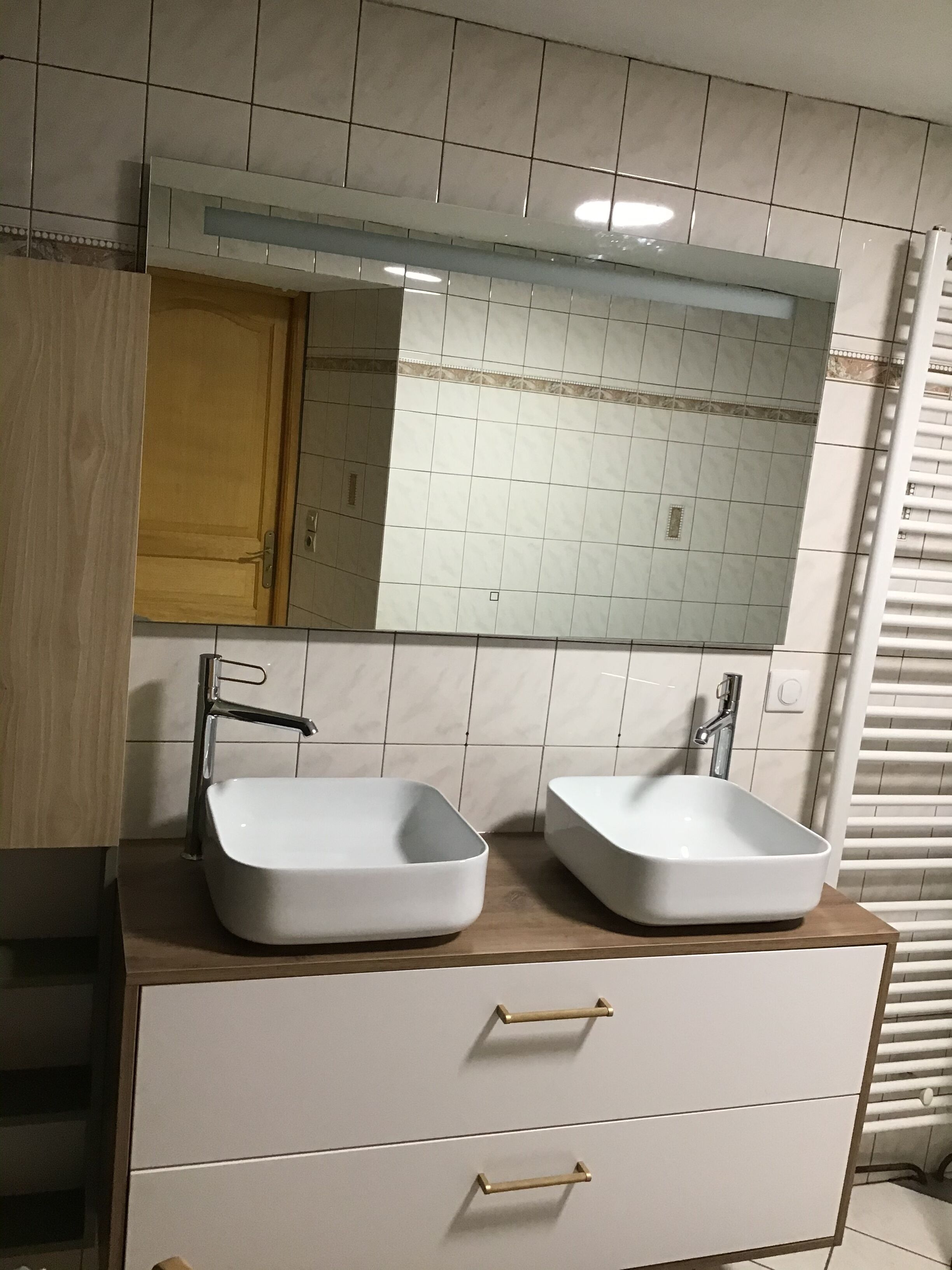 A bathroom with two sinks, a mirror, and a wooden cabinet.