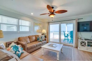 Relax in this inviting living room with a sofa, coffee table, and TV, plus a balcony with a view.