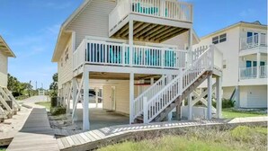 A two-story beachfront house with a wooden deck and a staircase leading to the upper level. - Oceanfront family-sized beach house (Cape San Blas)
