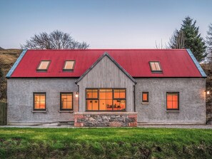 Ein Haus mit rotem Dach, Steinmauerwerk und mehreren Fenstern.