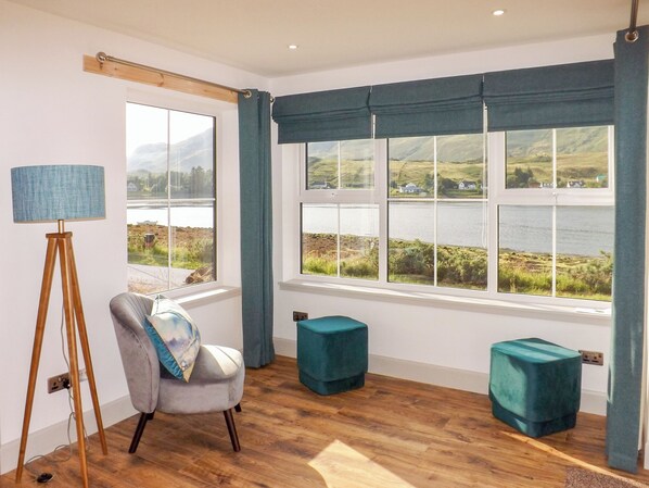 Ein Zimmer mit Blick auf einen See, eine Stehlampe, ein Sessel und zwei Hocker.