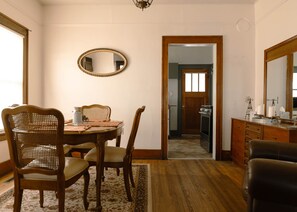 Uma sala de jantar com mesa de madeira, cadeiras, tapete e espelho na parede.