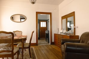 A dining area with a wooden table and chairs, a mirror, and a dresser with a mirror. - Red Roof Cottage – 2BR Mobridge Stay (Mobridge)