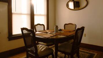 A dining room with a table, four chairs, a lamp, and a mirror on the wall.