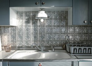 A kitchen with a large sink, a kettle, and a patterned backsplash. - Red Roof Cottage – 2BR Mobridge Stay (Mobridge)