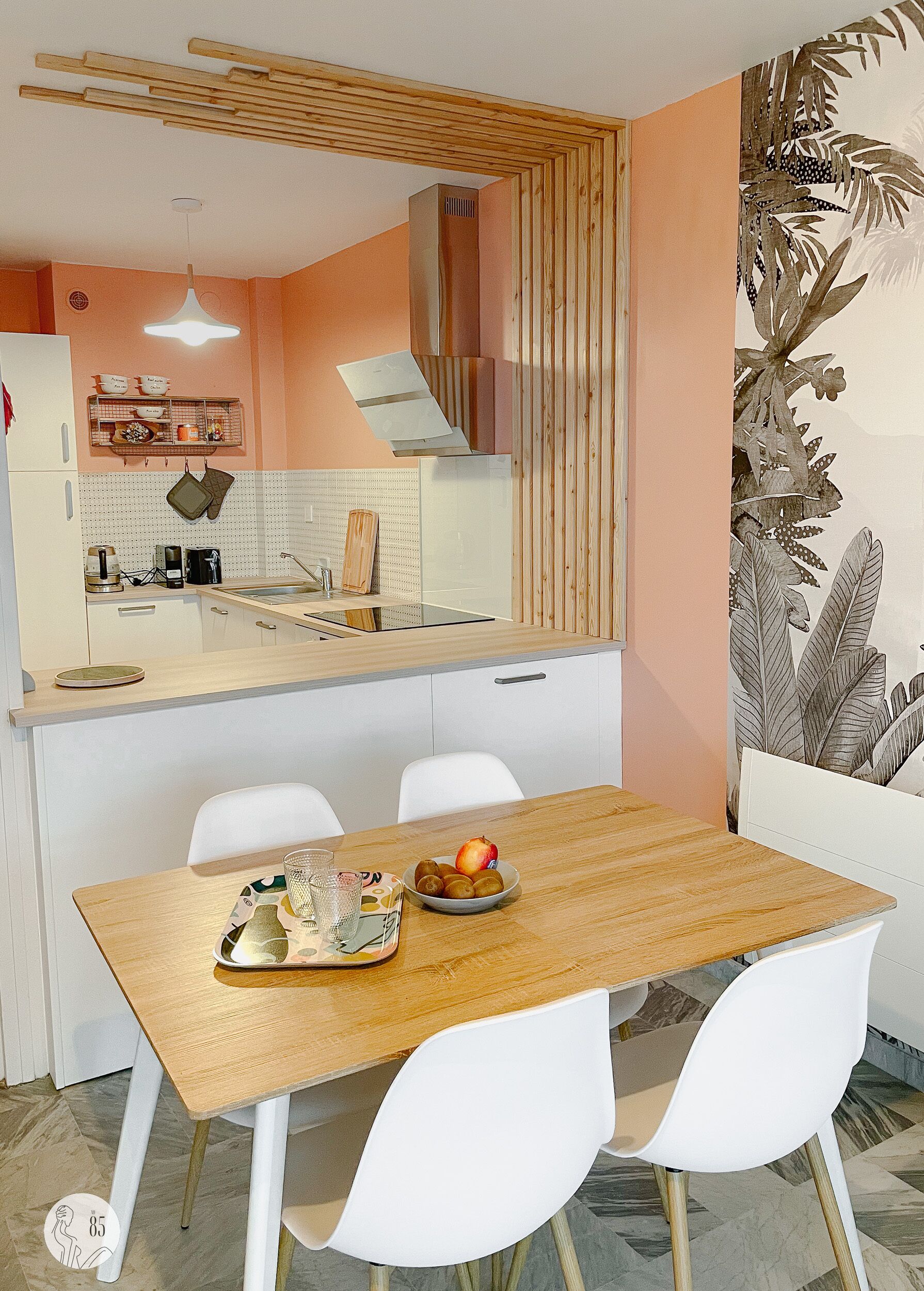 Een moderne keuken met witte kasten, een houten eettafel en een schaal fruit.