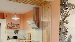 Una cocina moderna con armarios blancos, una mesa de comedor de madera y un frutero.