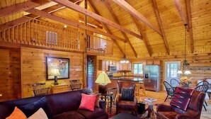 Ein Holzblockhaus-Innenraum mit Wohnzimmer, Küche und Essbereich.