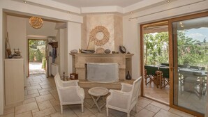 A cozy living room with a fireplace, white wicker furniture, and a view of the outdoors.