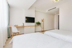 A hotel room with a bed, a desk with a chair, a TV, and a plant. - Liangxi Hotel (Kunshan)