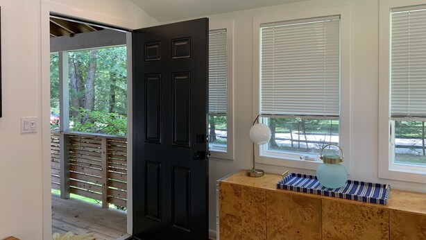 Een modern interieur met een zwarte deur, een houten vloer en een houten kast met een blauwe dienblad.
