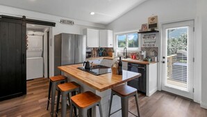 Una cocina moderna con una isla central, taburetes de bar, electrodomésticos de acero inoxidable y un letrero que dice 'Bienvenido'.