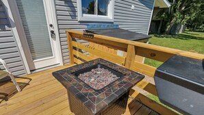 Una terraza con un pozo de fuego cuadrado y una parrilla.