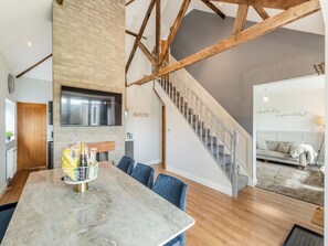 Un intérieur moderne comprenant un coin repas, une cuisine et un escalier.
