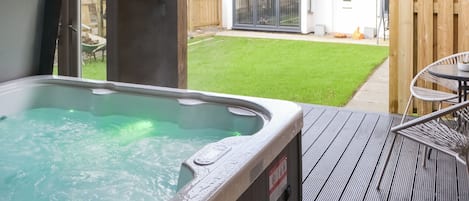 A hot tub with a view of a house and a lawn.